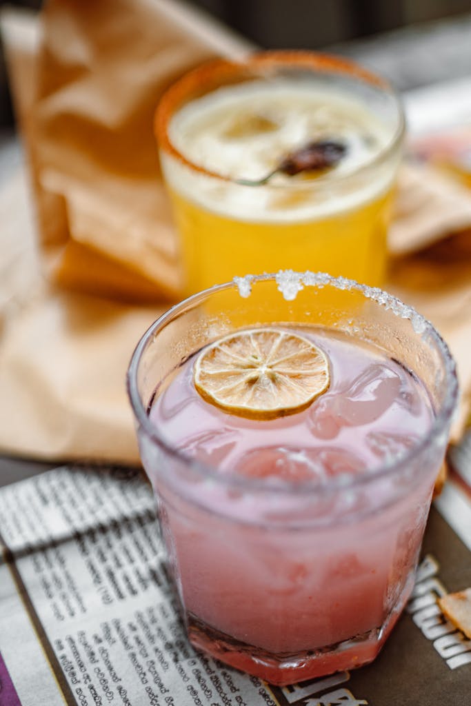 A close-up of two colorful cocktails with citrus slices and salted rims, perfect for summer.