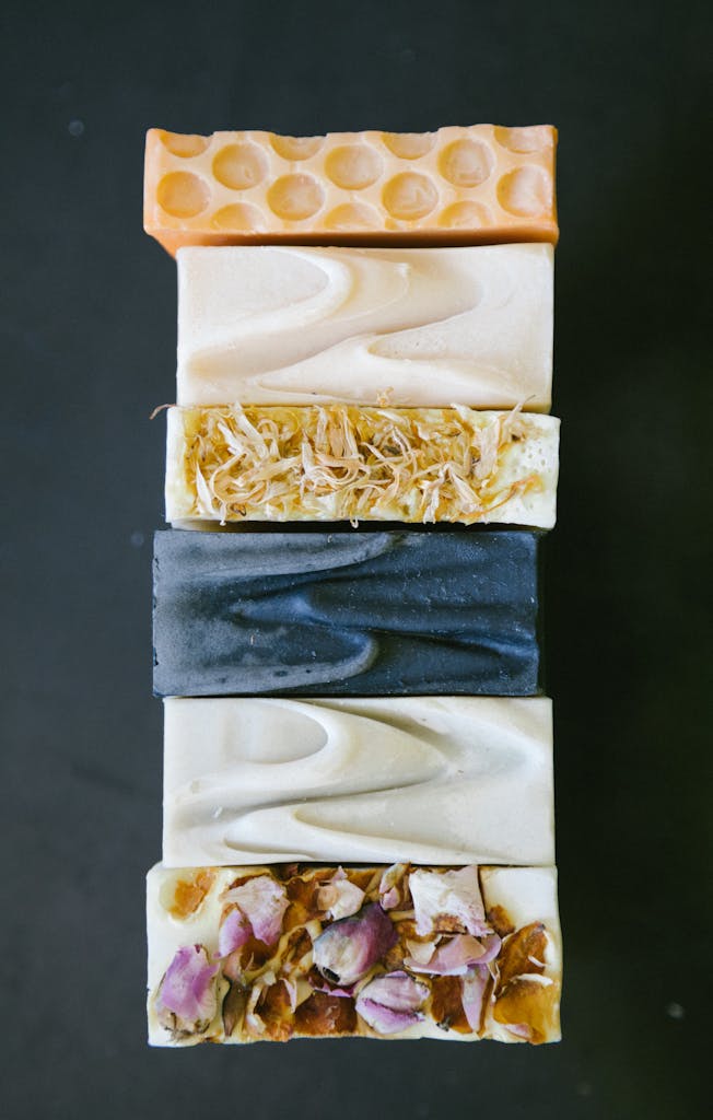 Close-up of assorted homemade organic bar soaps arranged vertically, showcasing natural textures.